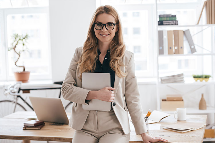 A businesswoman confidently poses with a tablet in a bright office setting, demonstrating modern vet training practices.