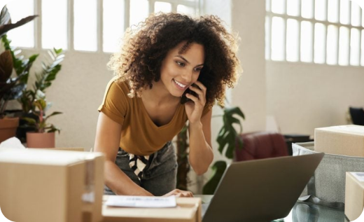 A woman works on a laptop and takes a phone call, demonstrating the support CAQA Courses offers to small business owners.