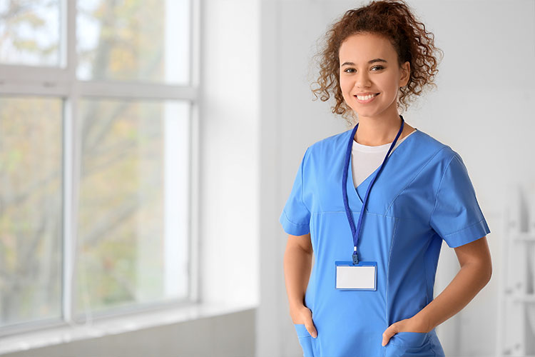 A smiling healthcare worker wearing scrubs demonstrates the practical application of vet training.